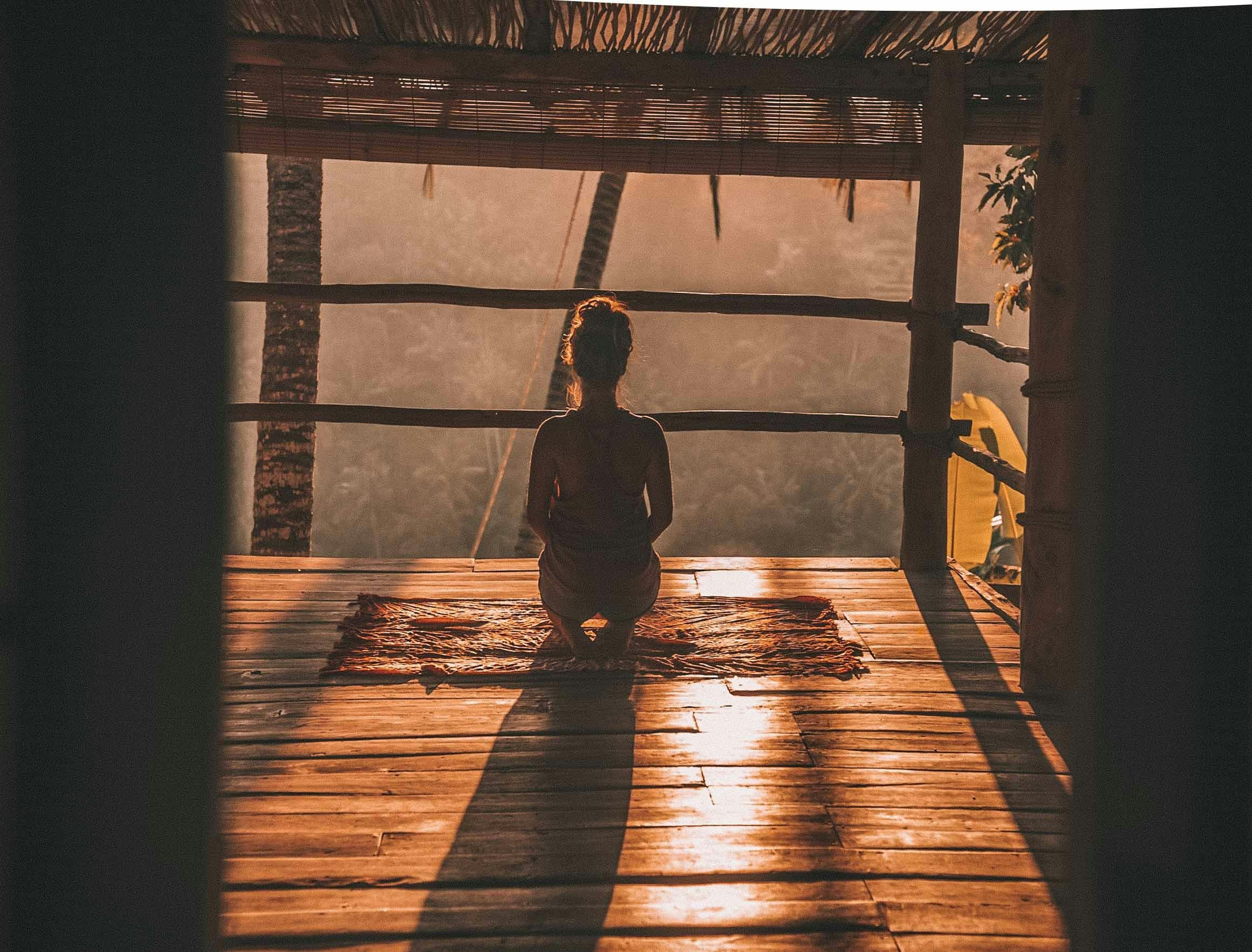 A woman sitting cross-legged in a quiet, sunlit room